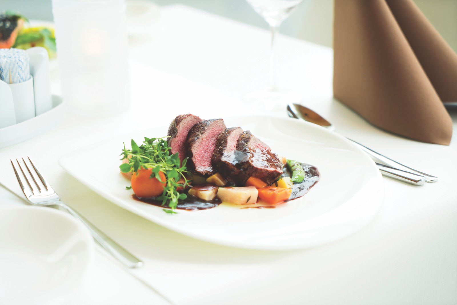 Starry Nights – Plated Entrée Sliced entrée with greens on a white plate in a fine dining room
